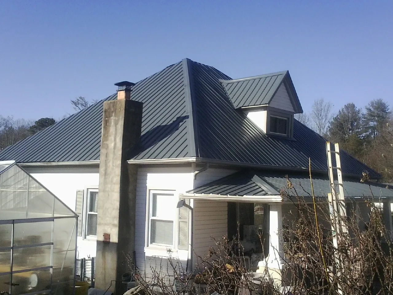 Dark blue standing seam metal roof on a white farmhouse with dormer — Slate & Tile Roof Repair by Roofing Brothers in Canonsburg