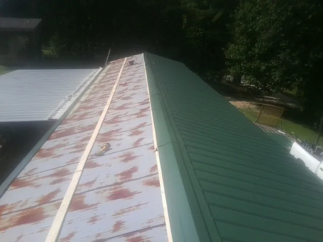Old rusted panels beside newly installed green metal roofing — Wind Damage Roof Repair by Roofing Brothers in Canonsburg