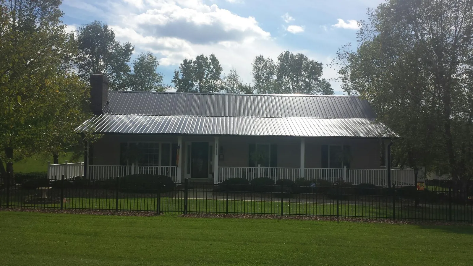 Gray metal roof on a brick ranch with a full width front porch — Gutter Guard Installation work by our crew in Canonsburg