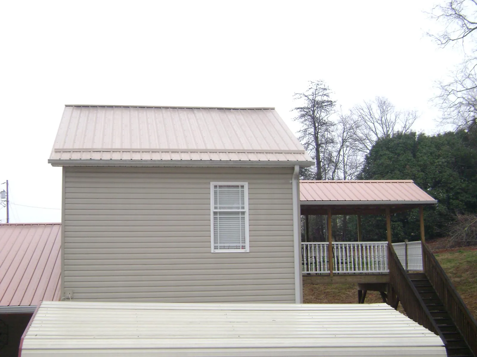 Tan metal roofs on a two story addition and attached porch, from a Roof Replacement job in Canonsburg