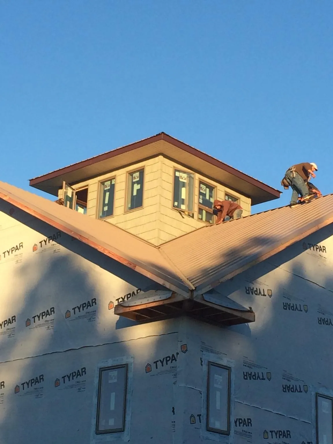 Roofers working around a rooftop cupola on a new metal roof at sunset — Roof Waterproofing in Canonsburg by Roofing Brothers